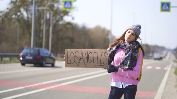 Jovem mulher bonita carona parando carro com cartaz Los Angeles
 - Filmagem, Vídeo