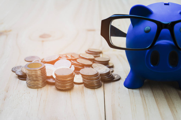 Blue piggy bank is placed on a wooden floor filled with coins pi - 写真・画像