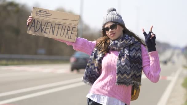Vonzó fiatal nő autóstoppos tartózkodás poszter kaland és jel győzelem.  - Felvétel, videó