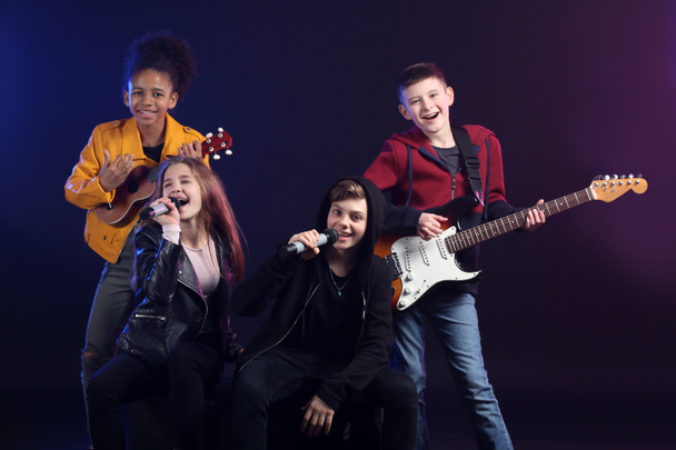 Teini-ikäisten muusikoiden ryhmä tummalla taustalla
 - Valokuva, kuva