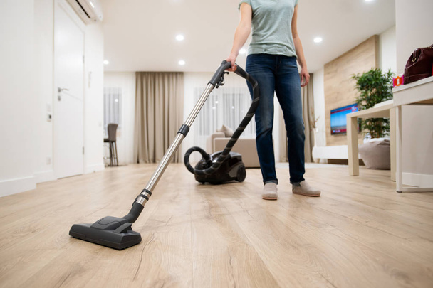 Wide angle photo of woman housewife or maid or service worker hoovering with vacuum cleaner in bright luxury appartment. - Fotografie, Obrázek