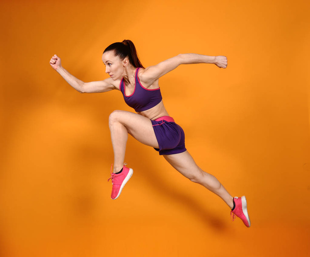Sporty running woman on color background - Photo, Image