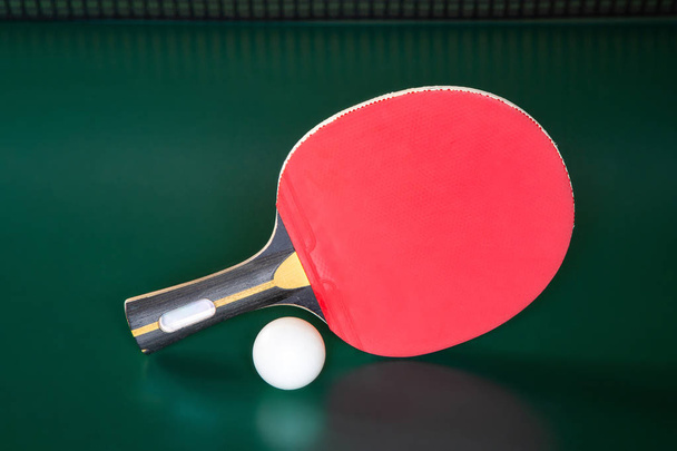 ping-pong racket and a ball on a green table. ping-pong net. - Foto, Imagen
