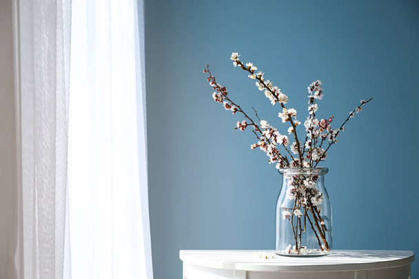 Vase with beautiful blossoming branches on table near window - Foto, afbeelding