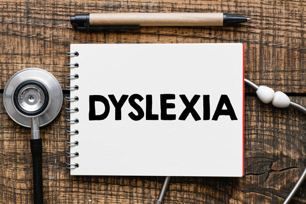 DYSLEXIA text in notebook, stethoscope and pen on wooden surface - Foto, afbeelding