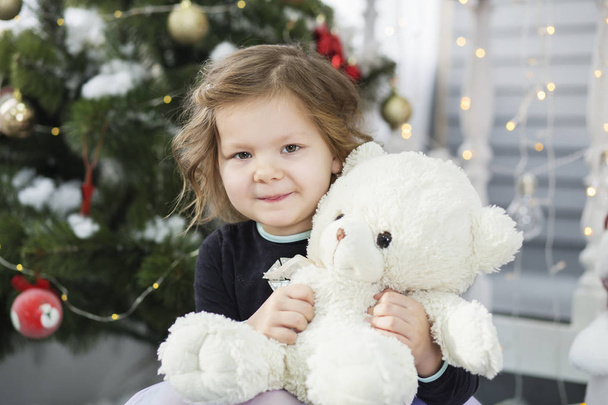 Πορτρέτο ενός χαριτωμένο κοριτσάκι αγκαλιάζει ένα μαλακό αρκουδάκι - Φωτογραφία, εικόνα