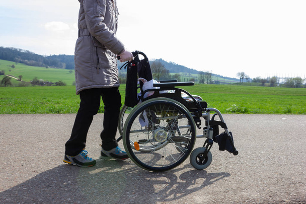 vanhempi nainen työntää pyörätuolia pyörätiellä Etelä-Saksassa keväällä
 - Valokuva, kuva