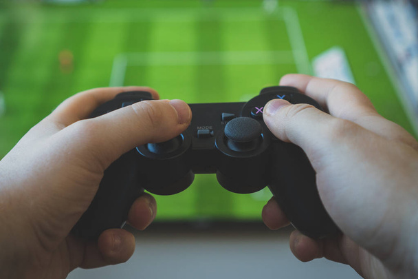 Homem jogando videogame de futebol na TV. Controlador Gamepad em mãos
. - Foto, Imagem
