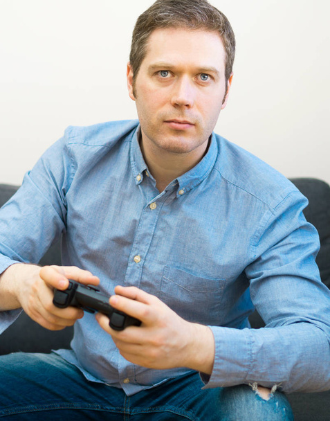 Mann spielt Videospiel mit Gamepad in der Hand. - Foto, Bild