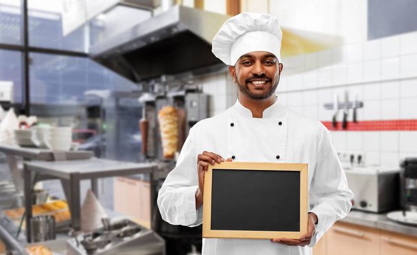 happy indian chef with chalkboard at kebab shop - Foto, imagen