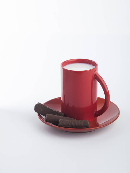 Beyaz üzerinde süt ve çikolata kurabiye ile kırmızı fincan. Üst görünüm. Boşluk Kopyala - Fotoğraf, Görsel
