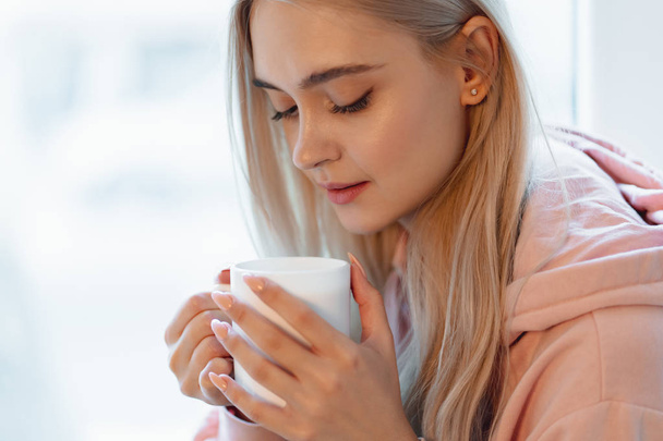 Elf podobne, młoda dziewczyna korzystających filiżankę kawy lub mleka, siedząc przy oknie - Zdjęcie, obraz