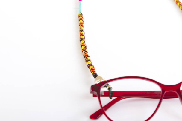lähikuva silmälasien pidikkeestä valkoisella taustalla
 - Valokuva, kuva