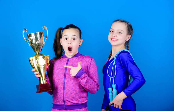 Deserved award. Girls athletic kids celebrate victory. Athletic girls with golden goblet. Win championship. Our team first place. Children gymnasts athletic kids happy champions. Sport achievement - Valokuva, kuva