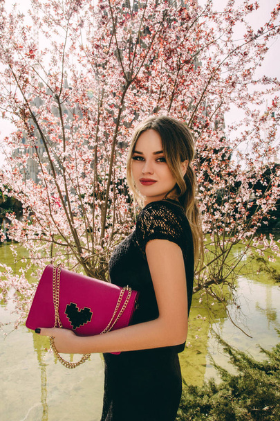 Young stylish woman posing on blooming spring tree background - 写真・画像
