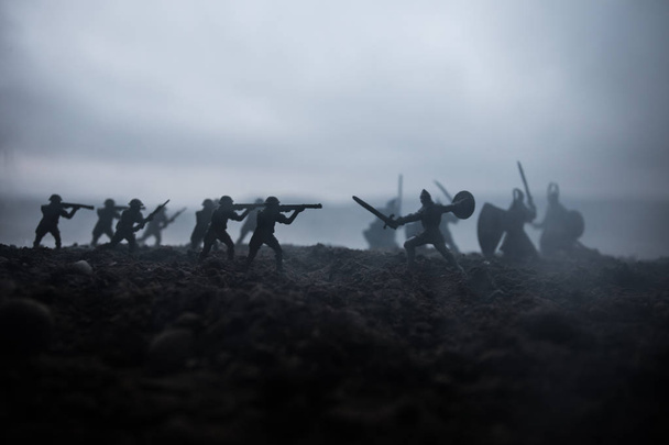 Battle scene. Military silhouettes fighting scene on war fog sky background. Creative concept. 20th century soldiers against medieval warriors. Artwork Decoration. - Photo, Image