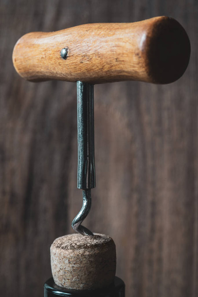 Bottle of wine with a corkscrew on blurry wooden background  - Photo, image