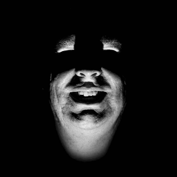Stylish portrait of adult caucasian man. He smiles like maniac and seems like maniac or crazy. Black and white shot, low-key lighting. Angry man, fear concept. Isolated on black. - Foto, Bild