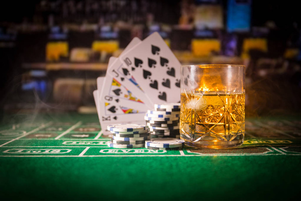 gambling, fortune, game and entertainment concept - close up of casino chips and whisky glass on table. Selective focus - Photo, Image