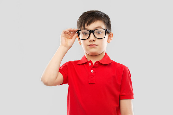 astonished boy in glasses and red t-shirt goggling - Foto, imagen