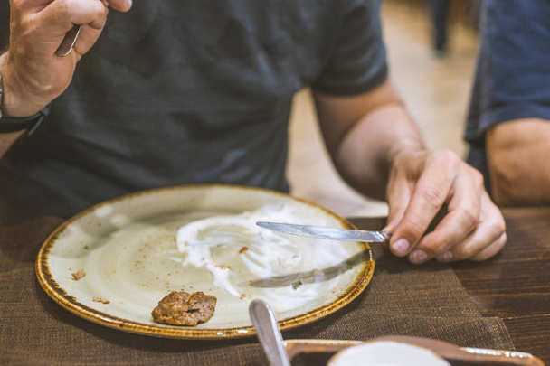 Man eating kebab with white sauce from clay plate in Middle East - Foto, afbeelding