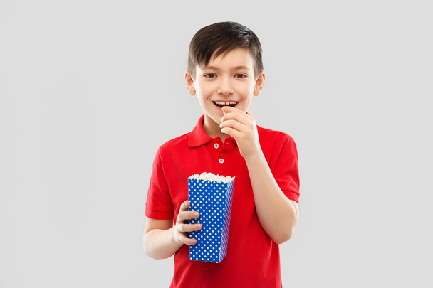 smiling boy in red t-shirt eating popcorn - Foto, imagen