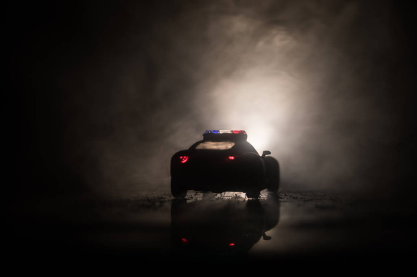 Αυτοκίνητα της αστυνομίας τη νύχτα. Το περιπολικό κυνηγούσε ένα αμάξι τη νύχτα με φόντο την ομίχλη. Αστυνομία Επείγουσας Ανάγκης με ταχύτητα στον τόπο του εγκλήματος. Επιλεκτική εστίαση - Φωτογραφία, εικόνα