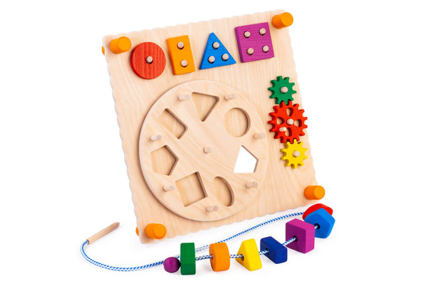 Drewniana ekologicznie zapracowana deska - zabawka edukacyjna dla dzieci, dzieci na białym, izolowanym tle, składająca się z wielokolorowych drewnianych elementów układanki, labiryntu, przekładni, sortownika - Zdjęcie, obraz