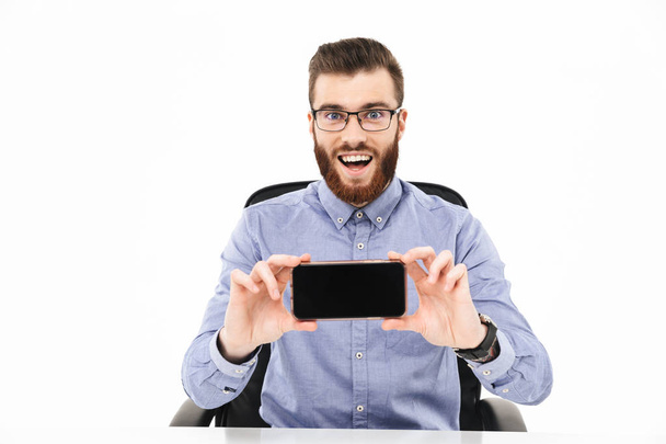 Surprised happy elegant man in eyeglasses showing blank smartphone screen - Valokuva, kuva
