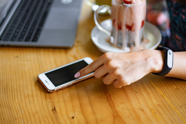 молодая женщина работает на ноутбуке, здоровый завтрак с семенами чиа и соком. Завтрак со смартфоном на ноутбуке. с помощью смартфона и ноутбука сенсорный дисплей
 - Фото, изображение