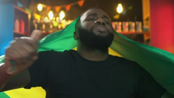 Afro-american sports fan with Brazil flag displeased about favorite team losing - Footage, Video
