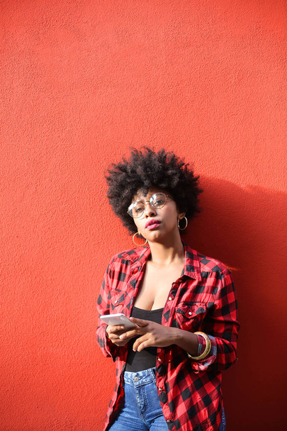 Piękna Afrykańska amerykańska dziewczyna z kręconymi włosami za pomocą smartfona - Zdjęcie, obraz