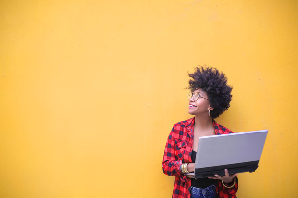 Mooi Afrikaans Amerikaans meisje met krullend haar houdt laptop - Foto, afbeelding