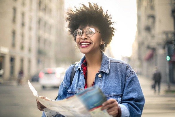 Красивая африканская американская девушка с кудрявыми волосами держит карту
 - Фото, изображение