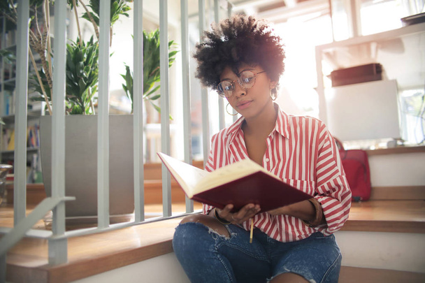 Menina americana africana bonita com cabelo encaracolado leitura
 - Foto, Imagem