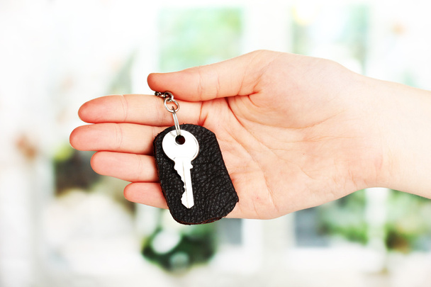 Key with leather trinket in hand on window background - Photo, Image