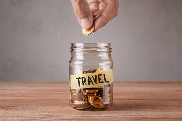 Travel. Glass jar with coins and an inscription travel. Man holds  coin in his hand - Photo, Image