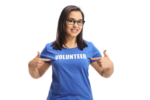 Young female volunteer pointing to her blue t-shirt isolated on white background - Foto, Imagen