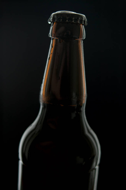 Μπουκάλι μαύρης μπύρας με σταγόνες νερού που απομονώνονται σε μαύρο φόντο με χώρο - Φωτογραφία, εικόνα