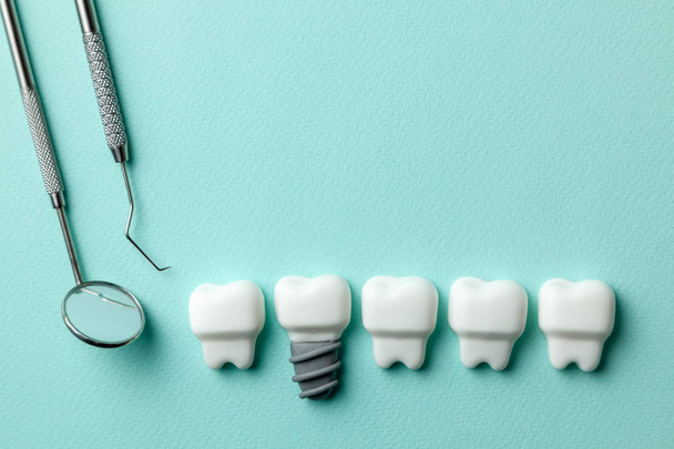 Zdravé bílé zuby a implantáty na zelené mátové pozadí a nástroje pro zubaře, hák. - Fotografie, Obrázek