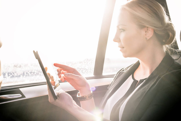 Businesswoman dotykając cyfrowego ekranu tabletu w samochodzie - Zdjęcie, obraz