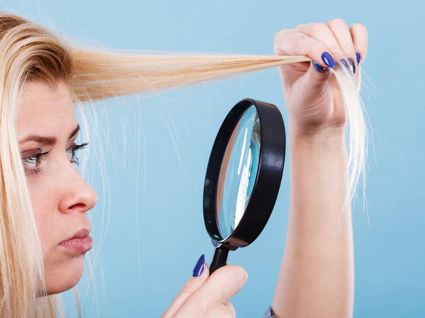 Woman looking at hair through magnifying glass - Foto, Bild