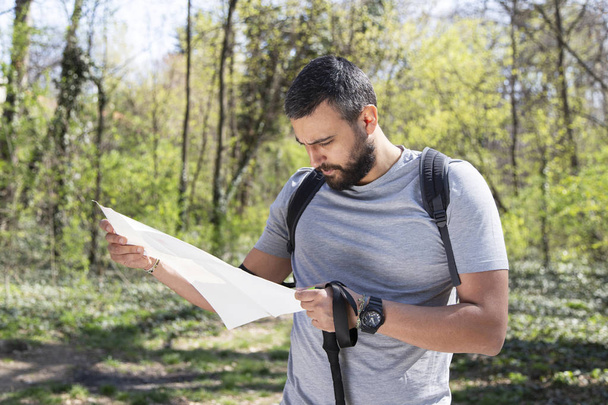 Male hiker using a map to locate the destination - Fotoğraf, Görsel