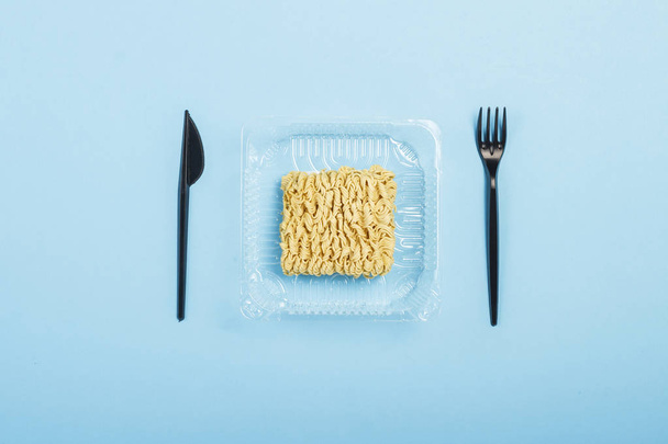 Tagliatelle istantanee asiatiche e piatti monouso in plastica su uno sfondo blu. Il concetto di cibi pronti, fast food, cibo spazzatura. Posa piatta, vista dall'alto
. - Foto, immagini