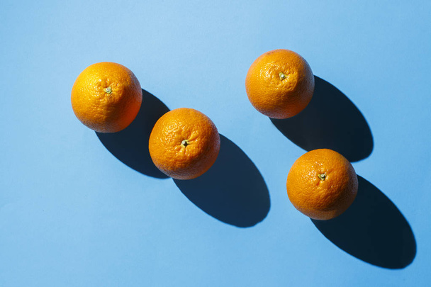 Oranges on a blue background. Hard light. Tropics concept, healthy food, breakfast, diet, vacation. Flat lay, top view. - 写真・画像