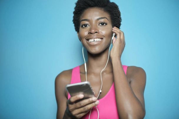 スマートフォンから音楽を聴く美しいアフリカ系アメリカ人女性  - 写真・画像