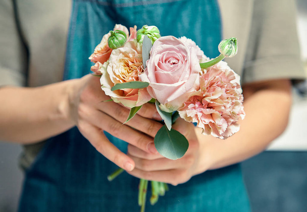 Selective focus on flower bouquet in female hands. Florist woman making bunch at shop. Flower shop, business, sale and floristry concept. Copy space for design - Photo, Image