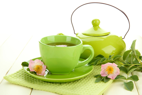 Cup and teapot of herbal tea with hip rose flowers on white wooden table - Foto, immagini