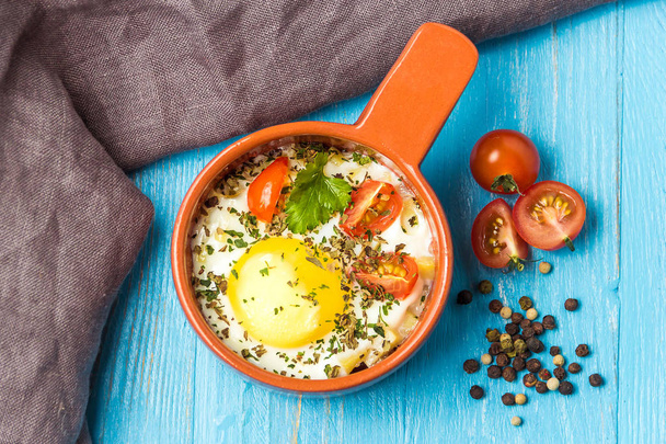 Portioned baked eggs in ceramic cocotte on blue wooden table, breakfast. Top view. - Foto, immagini