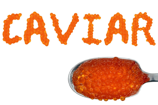 Kleine rote Fischeier bilden das Wort Kaviar. Löffel mit Rotstörkaviar. isolierter weißer Hintergrund - Foto, Bild